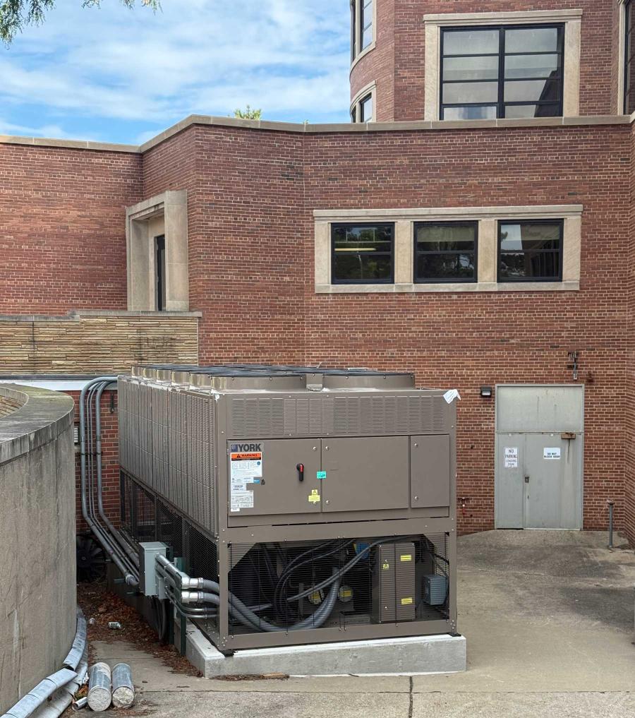 A large metal chiller outside the back of a brick building