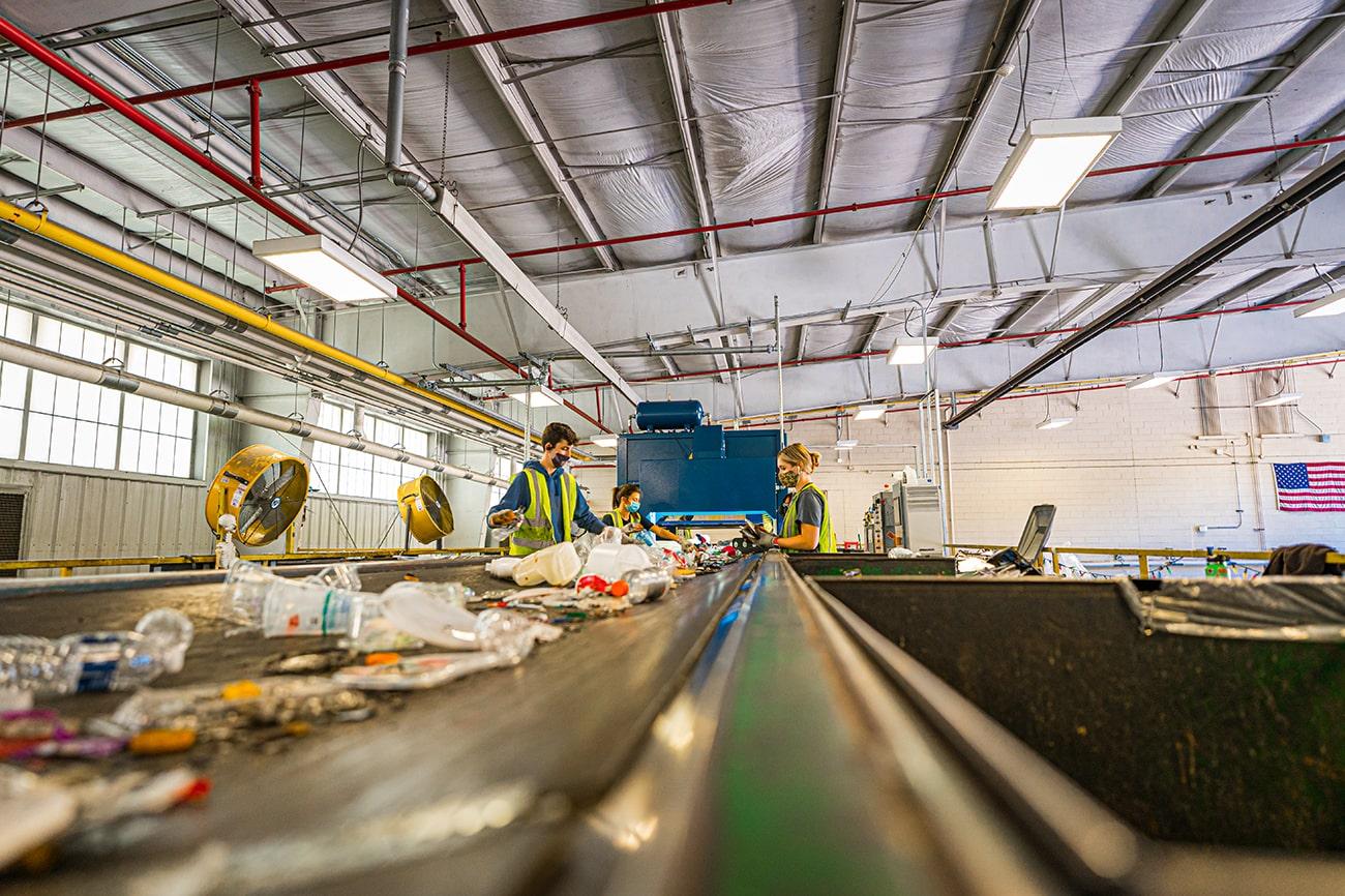 Workers at the MSU recycling center sort line with the robotic sorter.