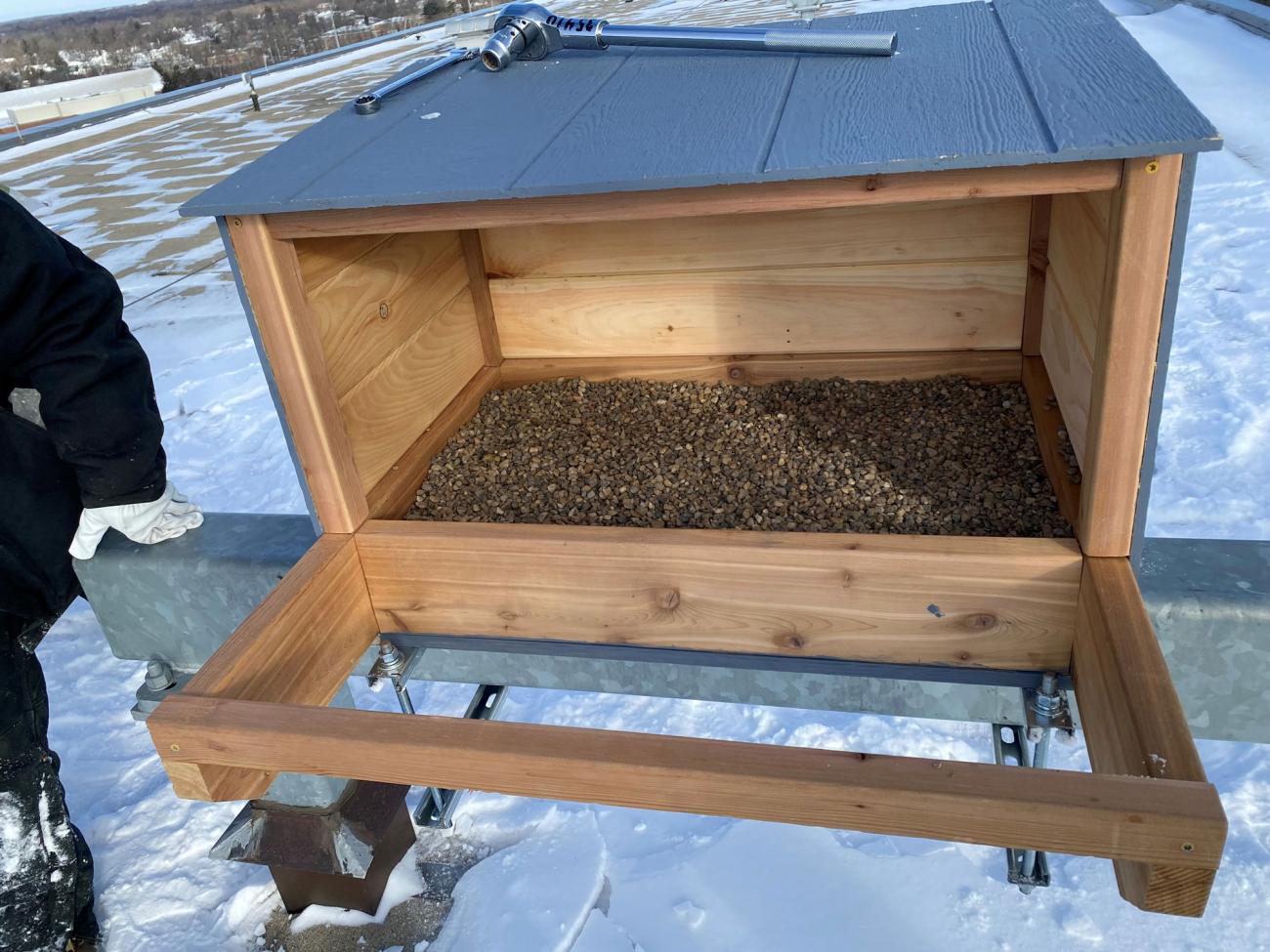 A rectangular pine box with a few inches of pea gravel on the bottom.