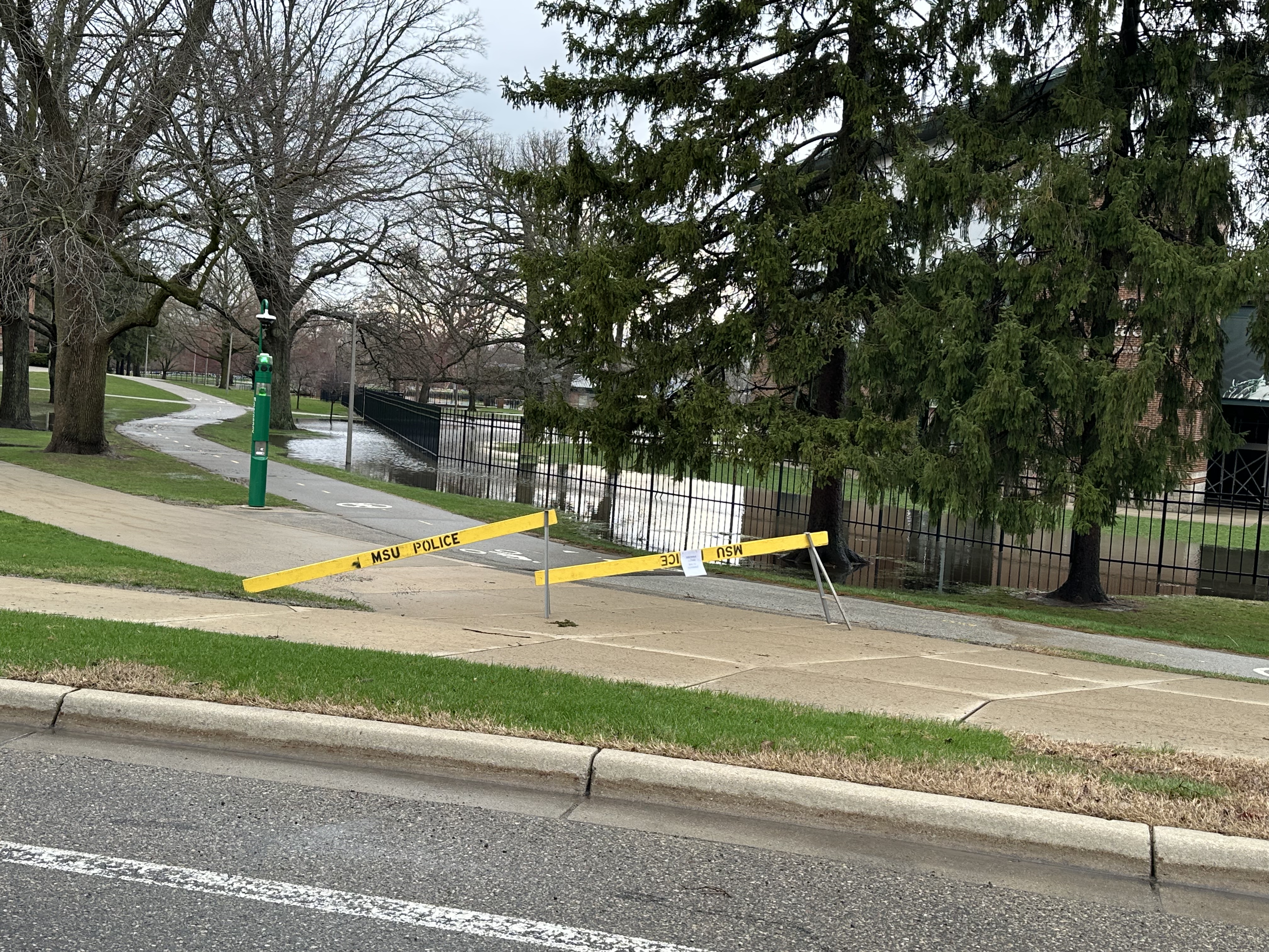 yellow police barricades across a walkway that is expected to flood as water levels rise on campus