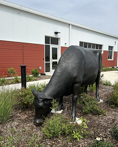 one statue is posed as if grazing from the flowerbed around it