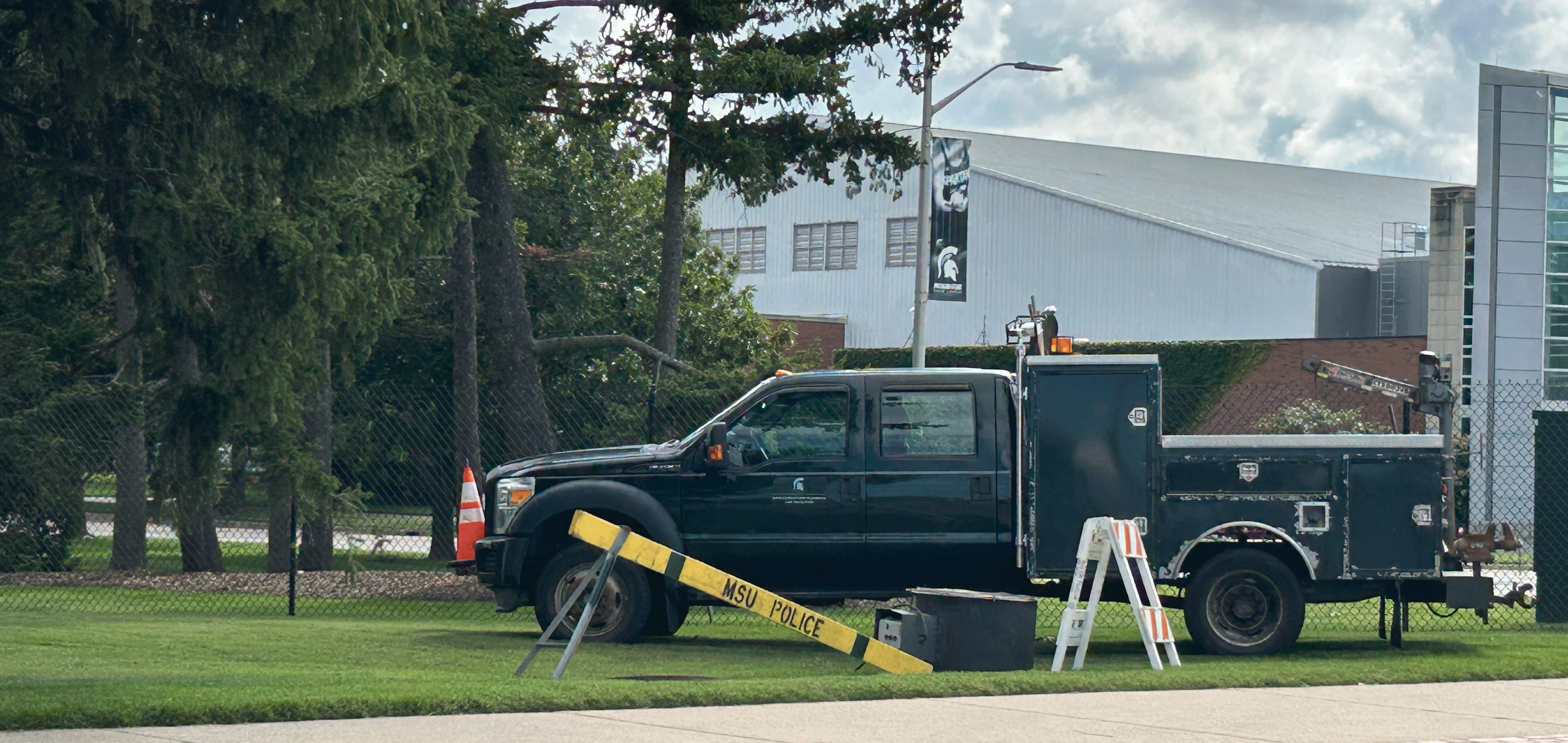 utility truck parked in the grass with a police barricade