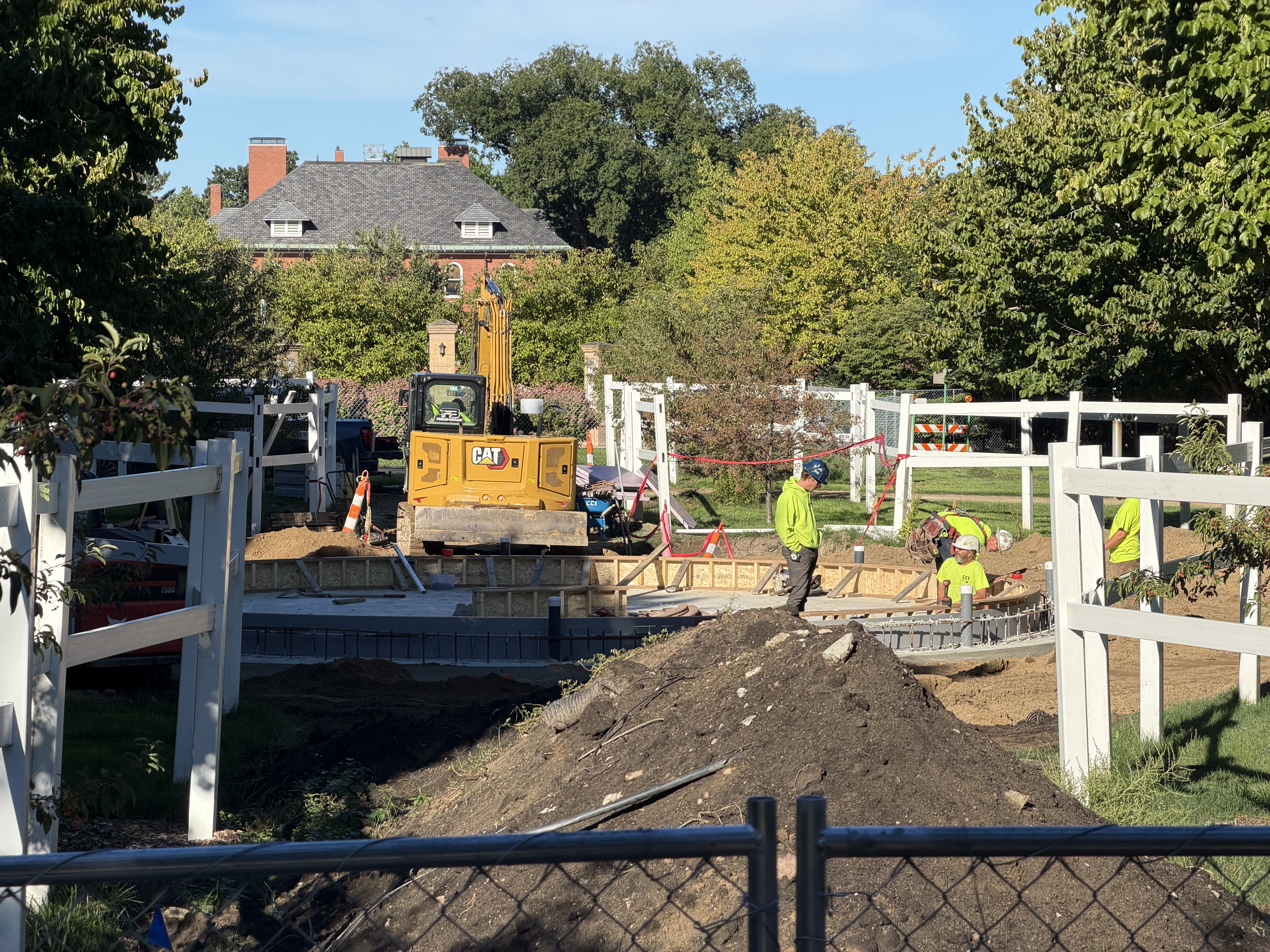 large pile of dirt in the forefront of the image with construction teams working to create the fountain