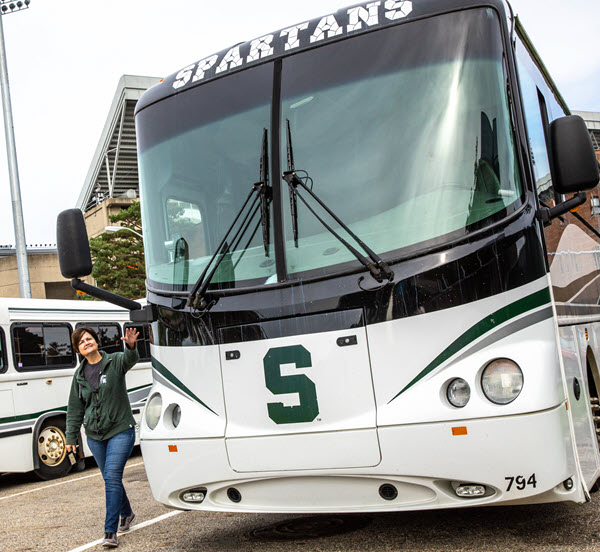Deb Rowe performing a pre-trip inspection of the exterior of an MSU bus