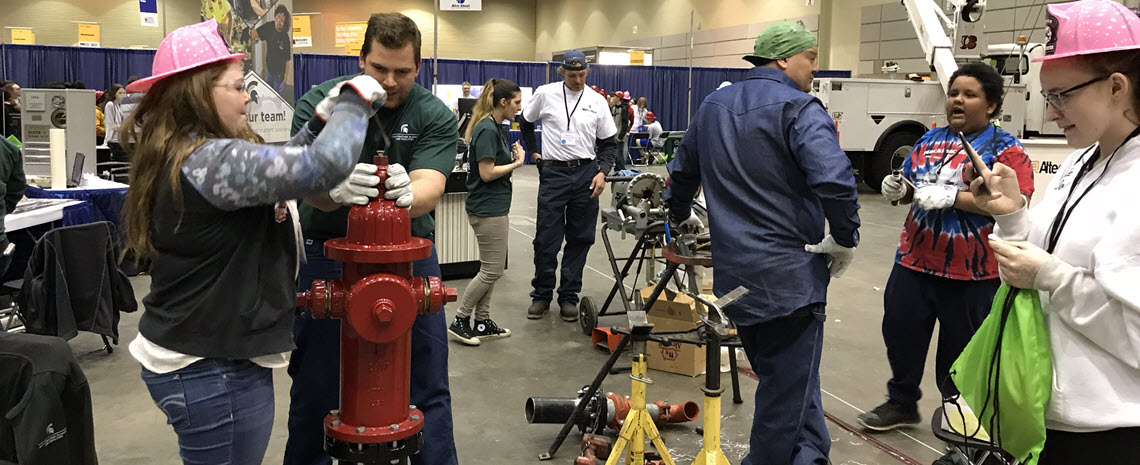 Photo of Outside Weld's Ryan Pung helping student assemble a fire hydrant