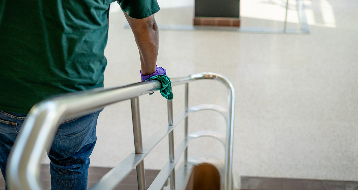 Custodial Services employee cleaning handrail in MSU Library
