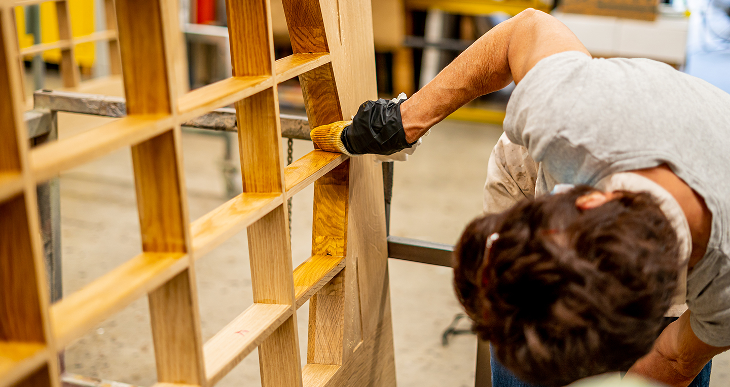 Pam Hebeler staining MSU auditorium door inside MSU IPF Paint Shop