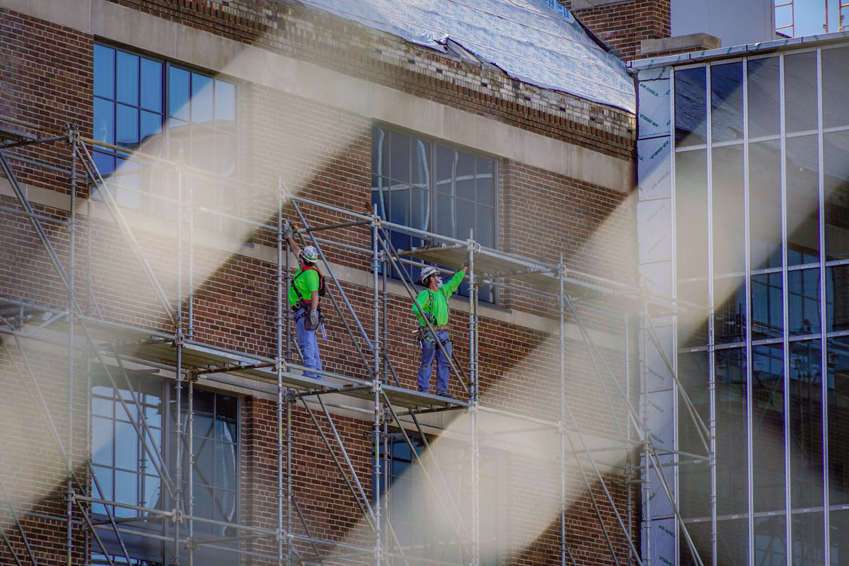 Construction workers working on windows of the STEM facilities' old Power Plant section