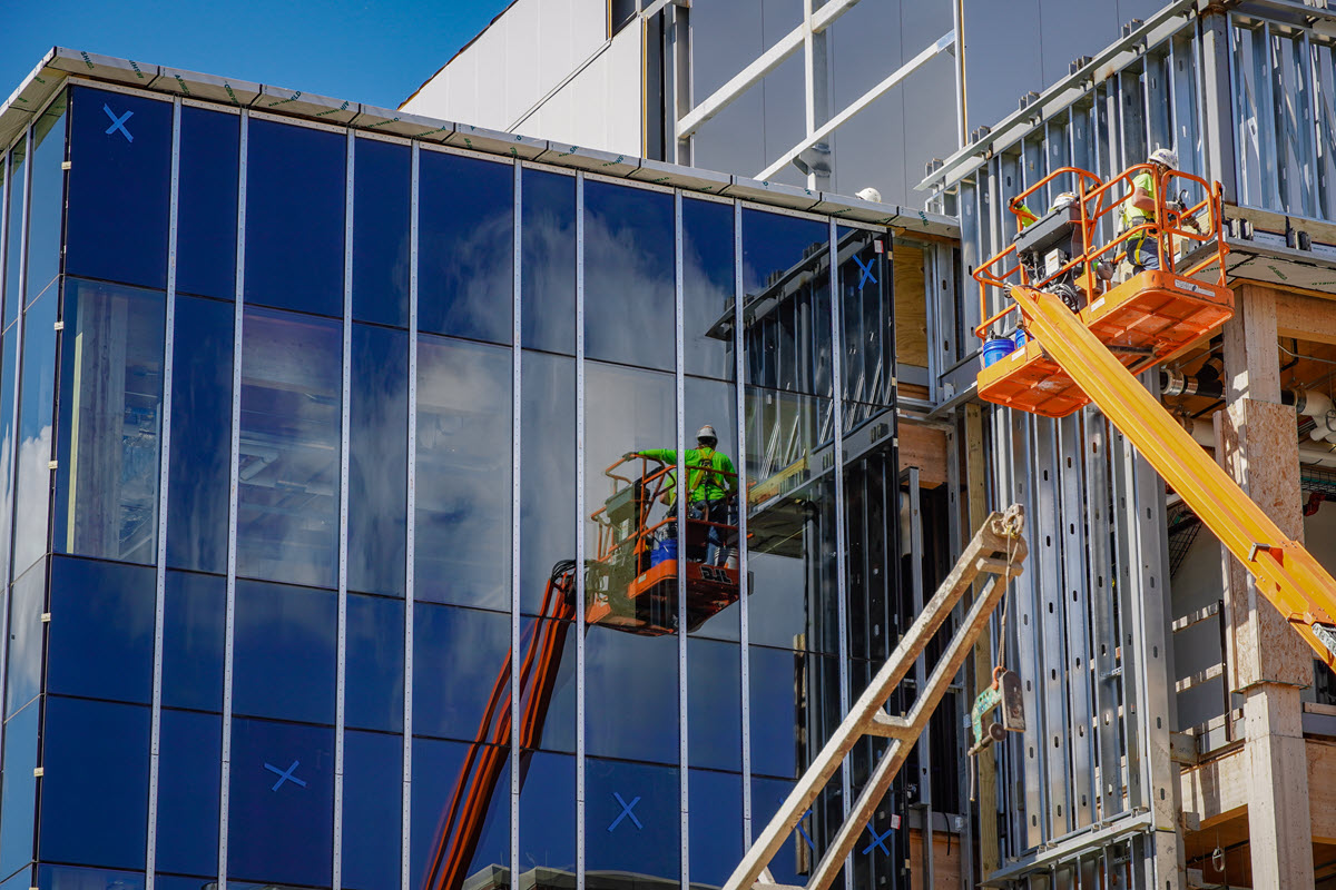 Construction workers working on glass wall section of STEM facility
