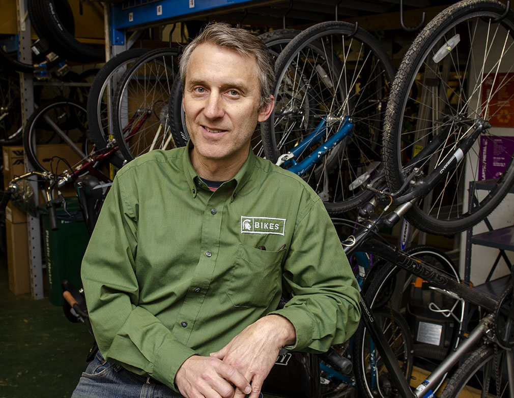 Tim Potter sitting in front of a rack of bicycles