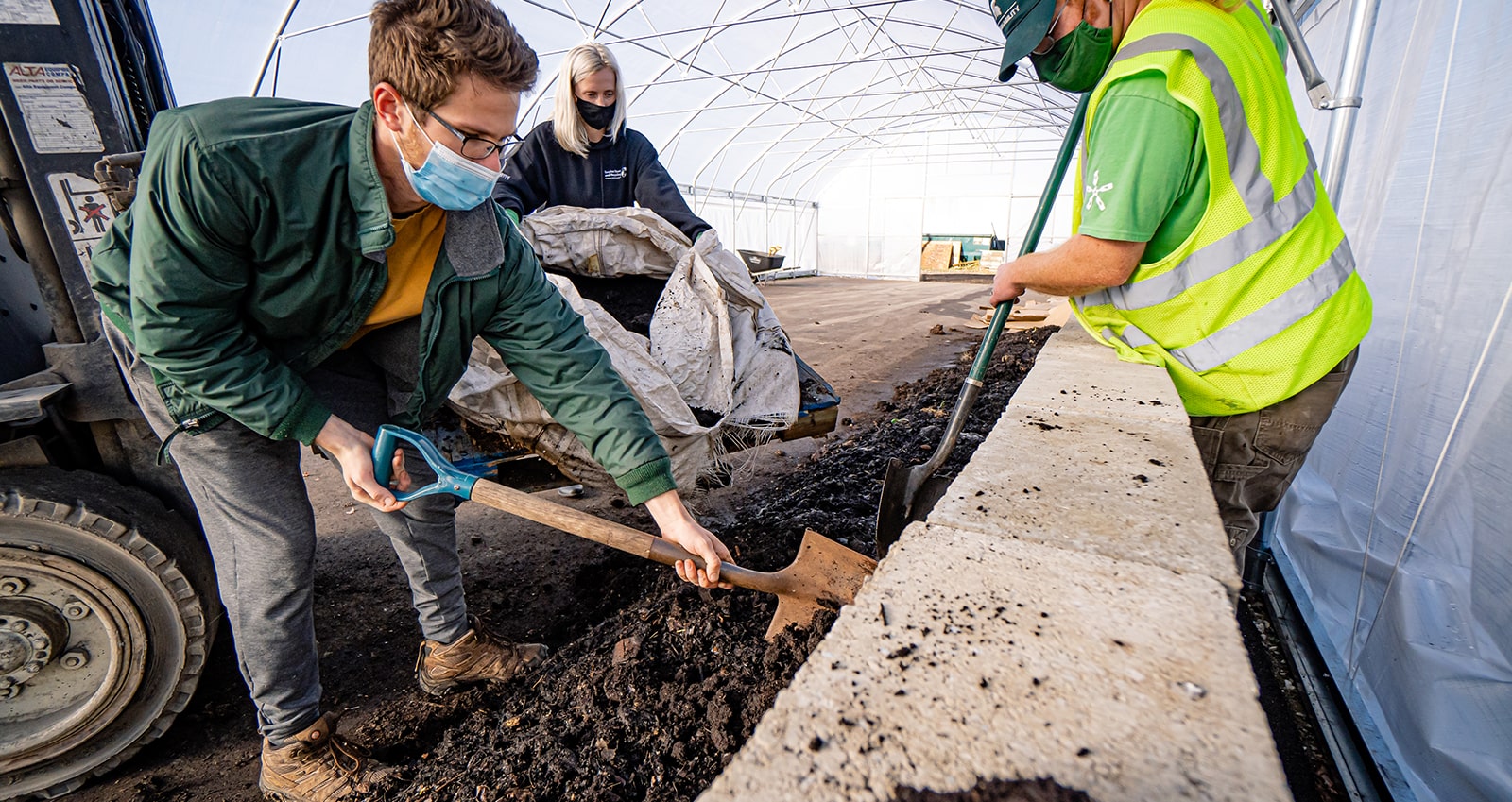 Workers using shovels to remove worms from worm bag