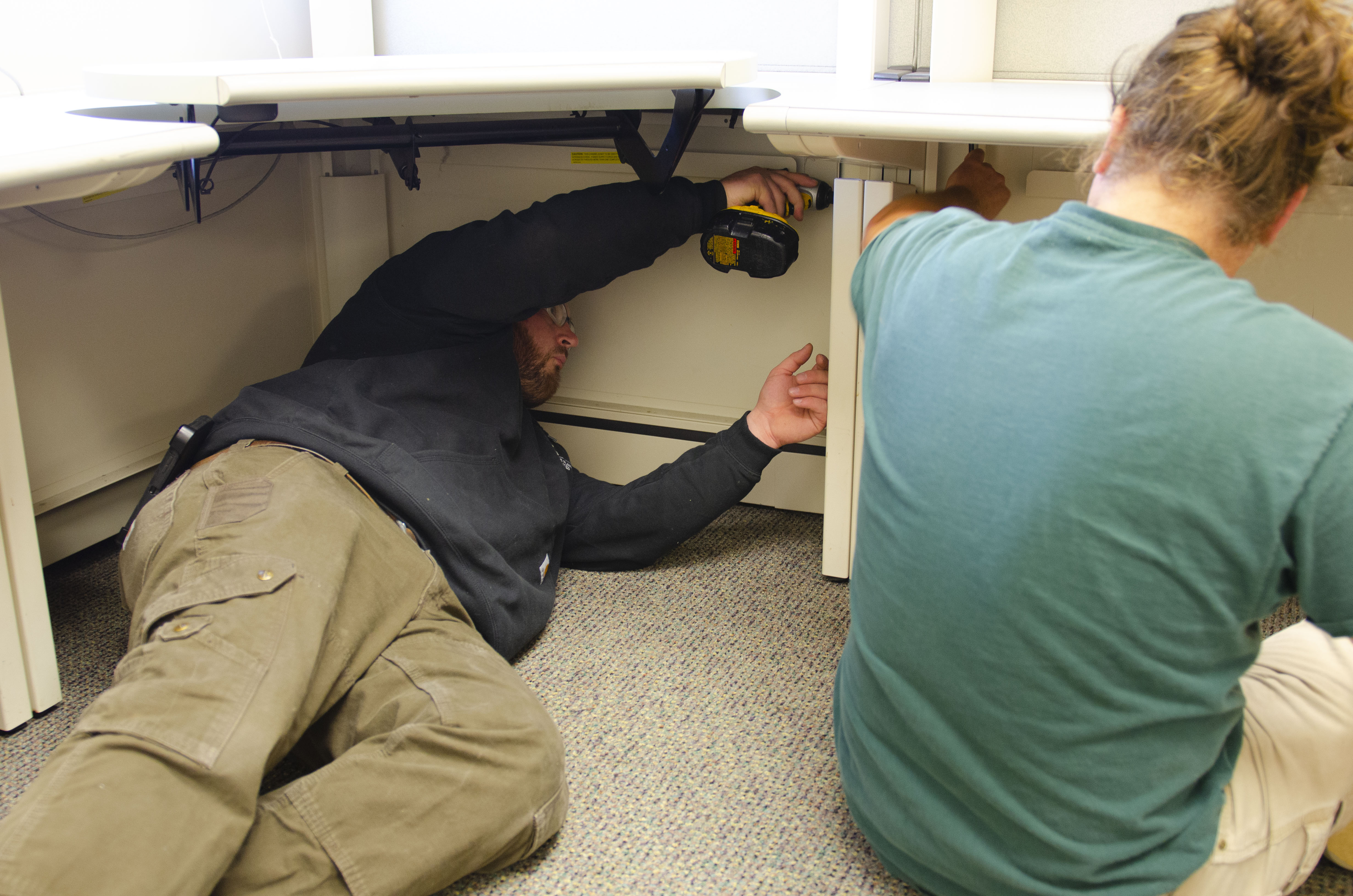 Josh Radon and Tom Cousins moving cubicle furniture in a faculty office