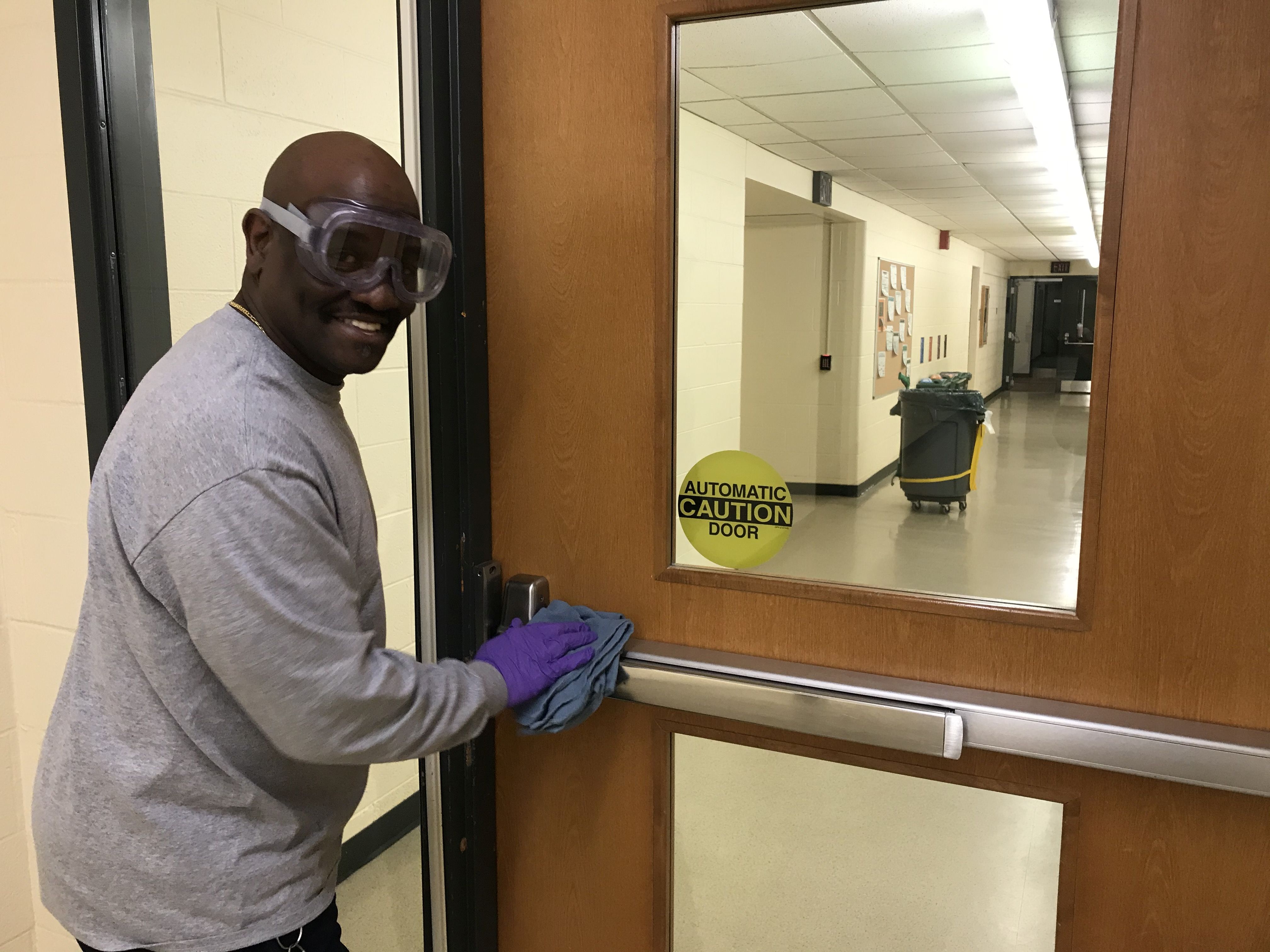 Custodial Services staff member cleaning door handles at Spartan Village