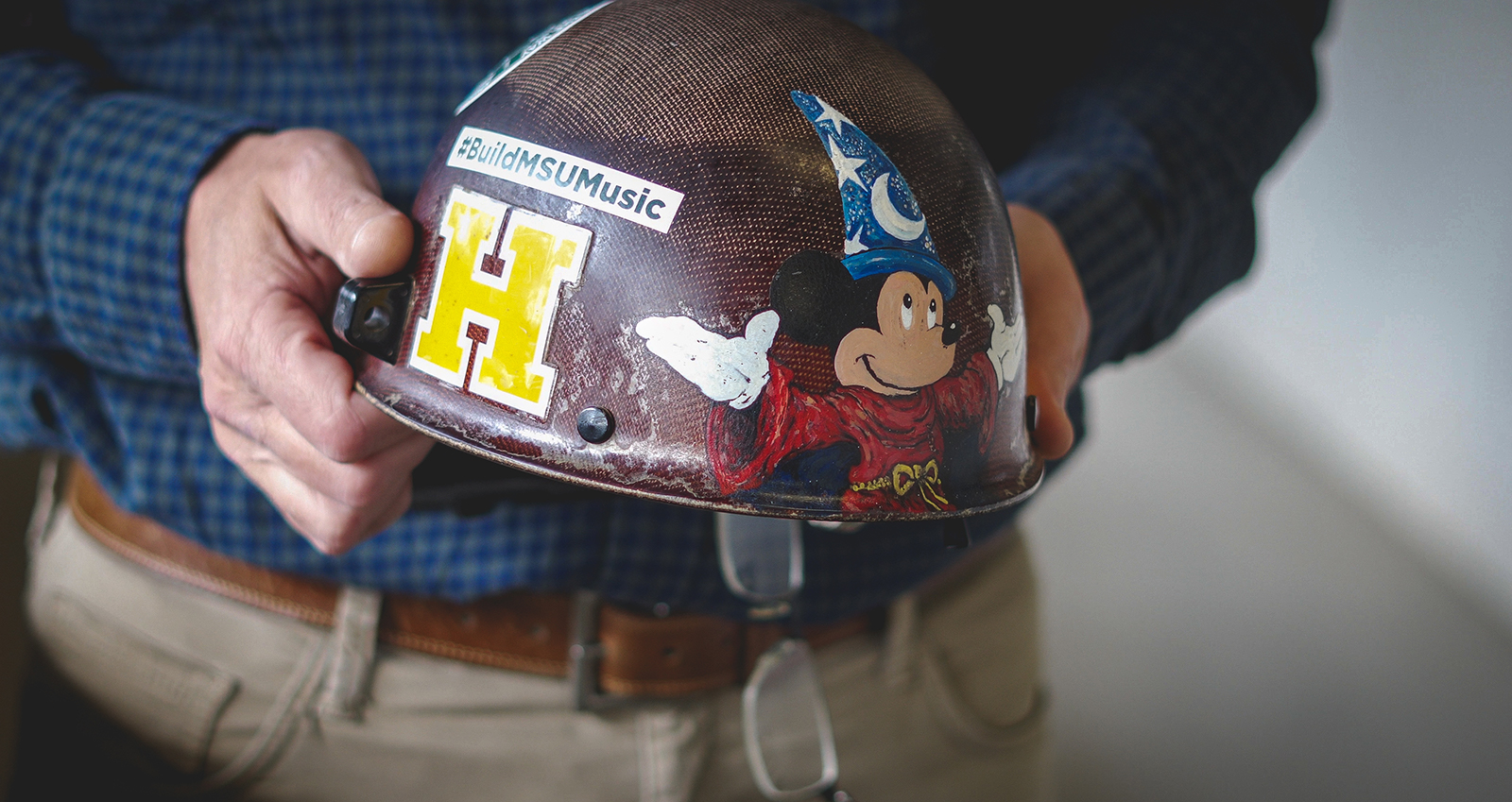 Todd Wilson holding his father's hard hat at an angle.