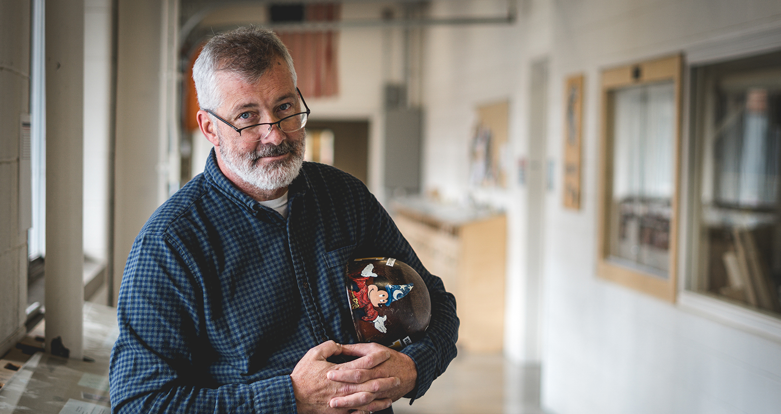 Todd Wilson holding his father's helmet in the crook of his arm