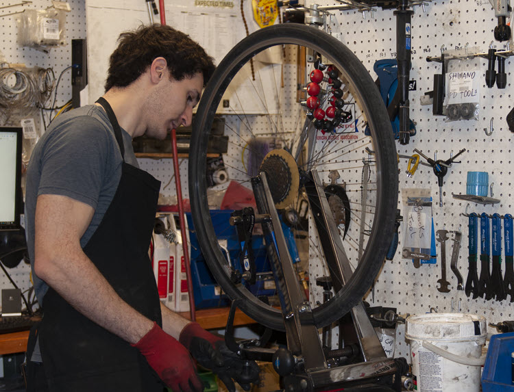 Photo of MSU Bikes student staff member Alex Smith working on bicycle