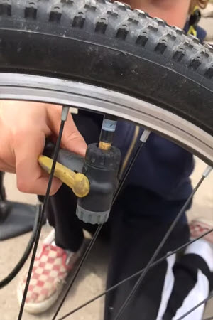 child putting air into bicycle tire
