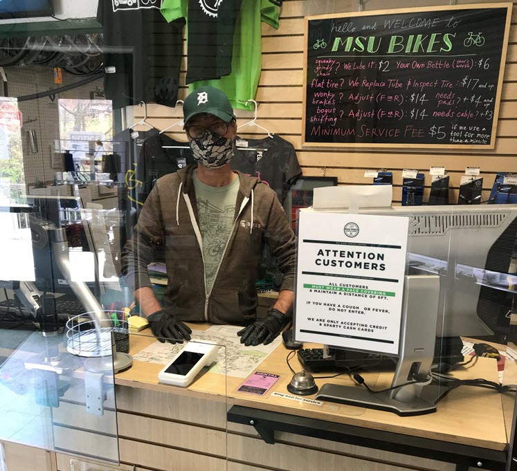 Aubrey Hoermann standing behind the Service Center's plexiglass shield wearing a face mask and gloves.