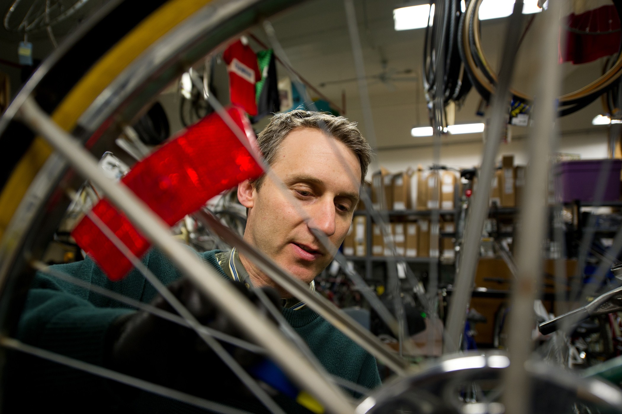 Tim Potter being photographed through the spokes of a bicycle wheel