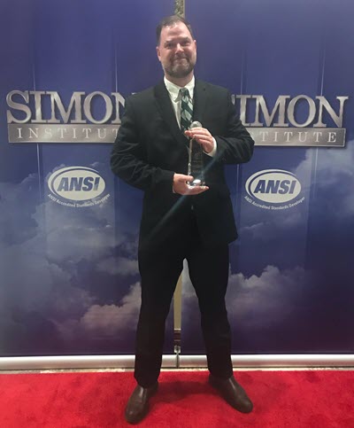 Photo of Josh Sego holding his trainer of the year award at the Simon Institute event