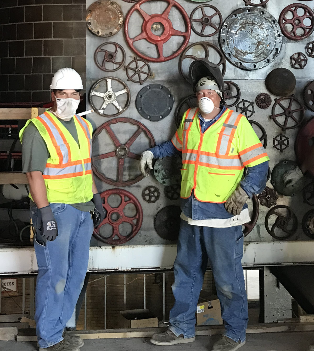 Photo of IPF pipefitters/welders Ryan Pung and Jason Pohl standing in front of the STEM art piece they fabricated
