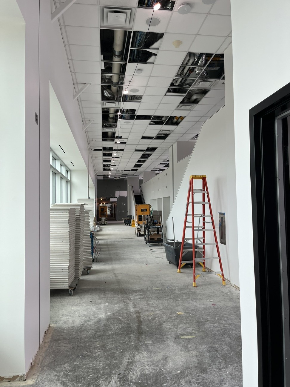 interior space under construction with completed drywall, concrete floor and drop ceiling in progress