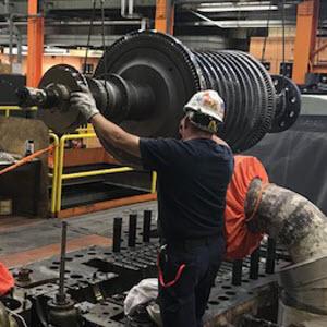 Photo of power plant worker using hoist to lift turbine rotor out of its housing