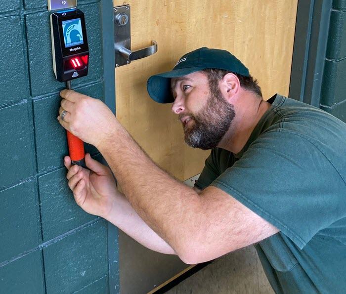 Eric Simmon installing biometric scanner in Jenison Field House