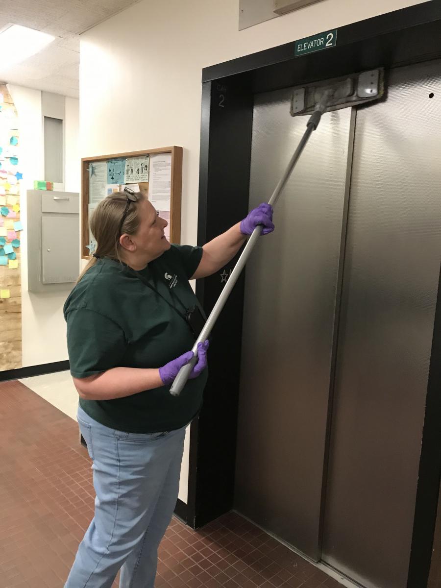 Custodial Services staff member cleaning elevator doors