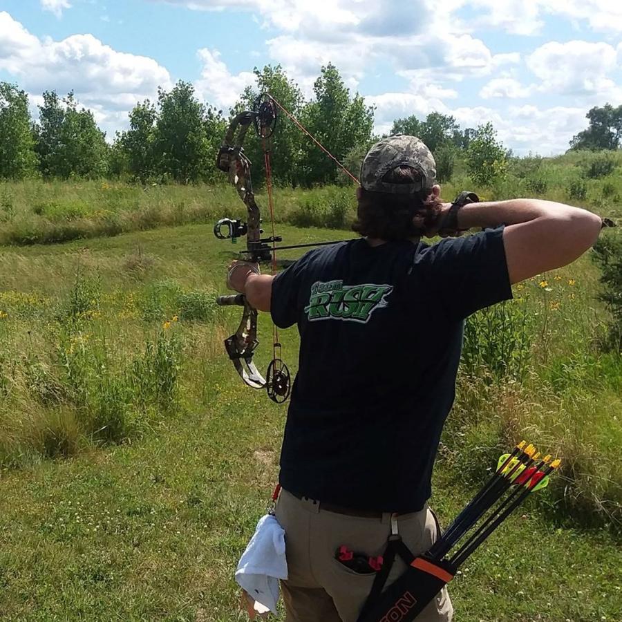 Person drawing a bow on an outdoor target