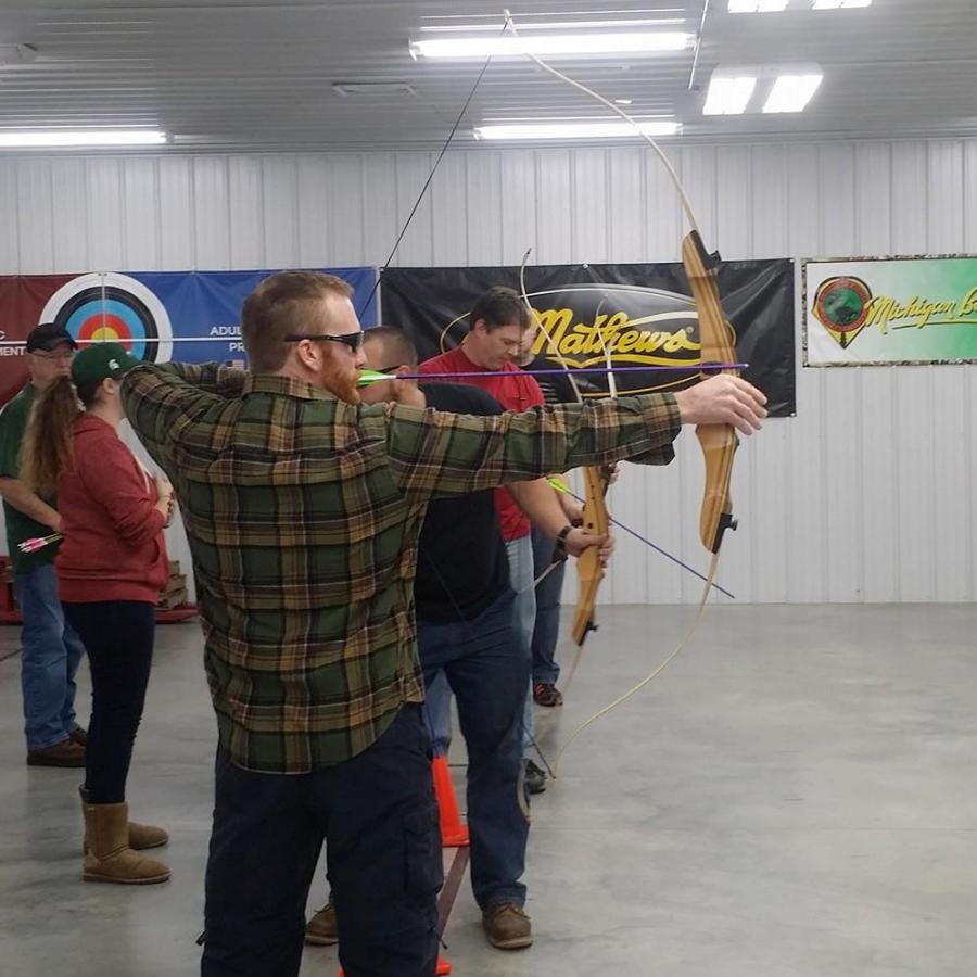 Man drawing a bow with an arrow at a target