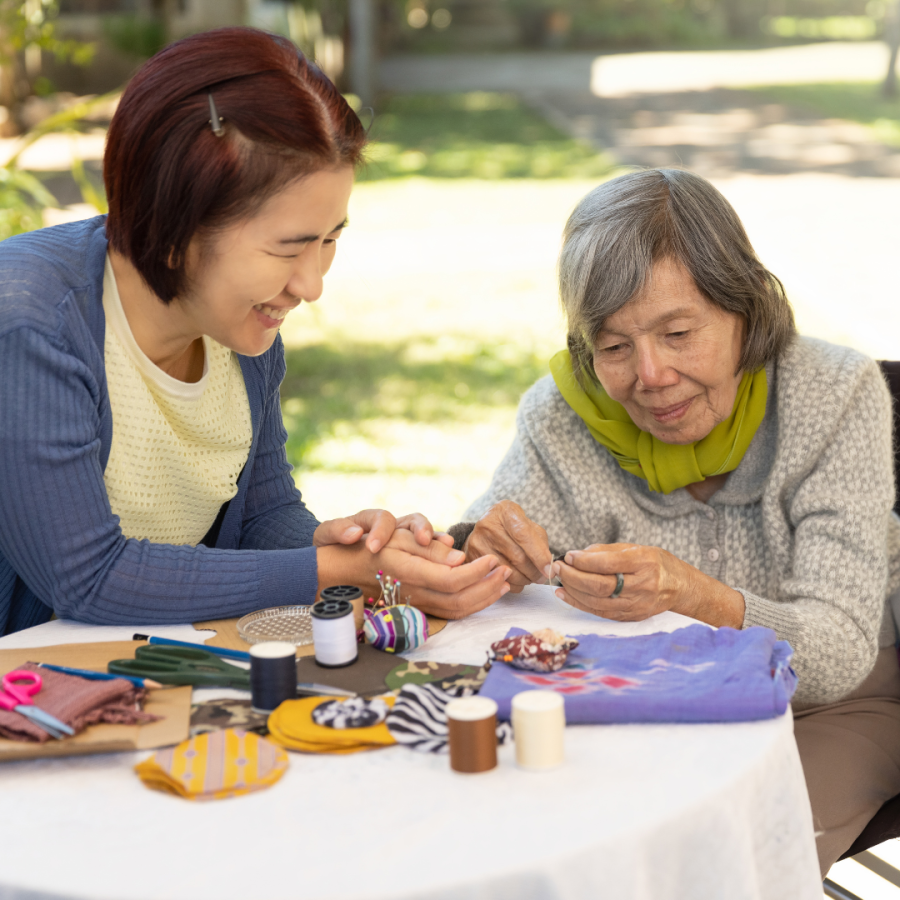 A women helping an elderly woman with an activity.