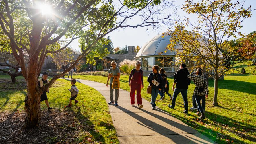 Families enjoy a peaceful walk near the HLG Conservatory at sunset.