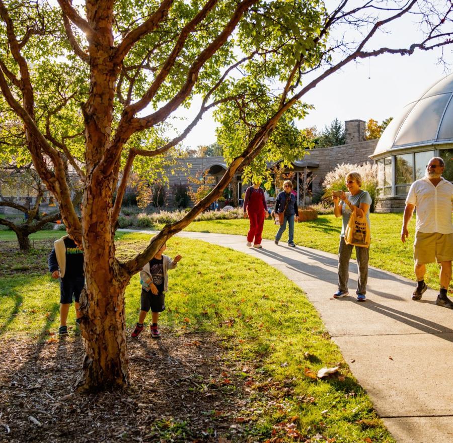 Families enjoy a peaceful walk near the HLG Conservatory at sunset.