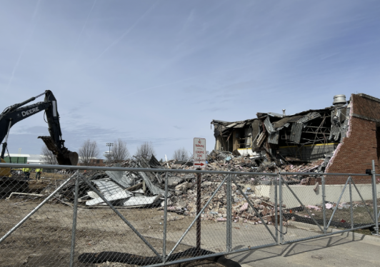 Gated demolition site with half torn down brick building