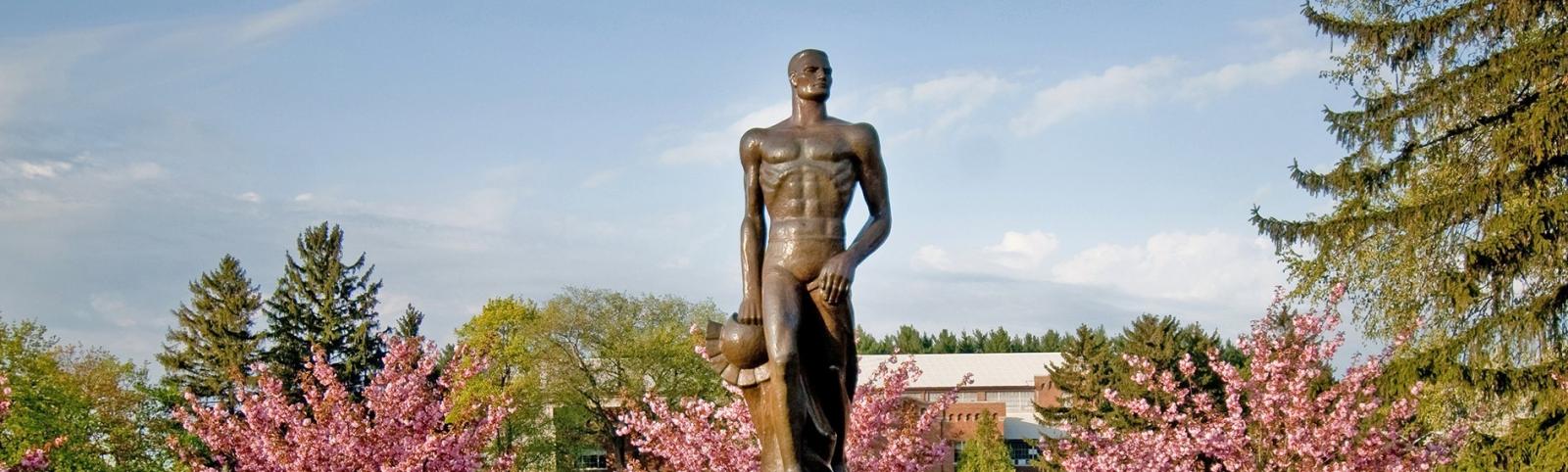 Photo of Sparty statue against background of flowering trees