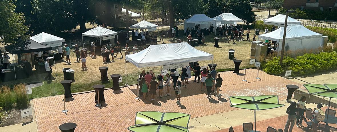 outdoor event with tents, tables, food vendors and signage in People's Park