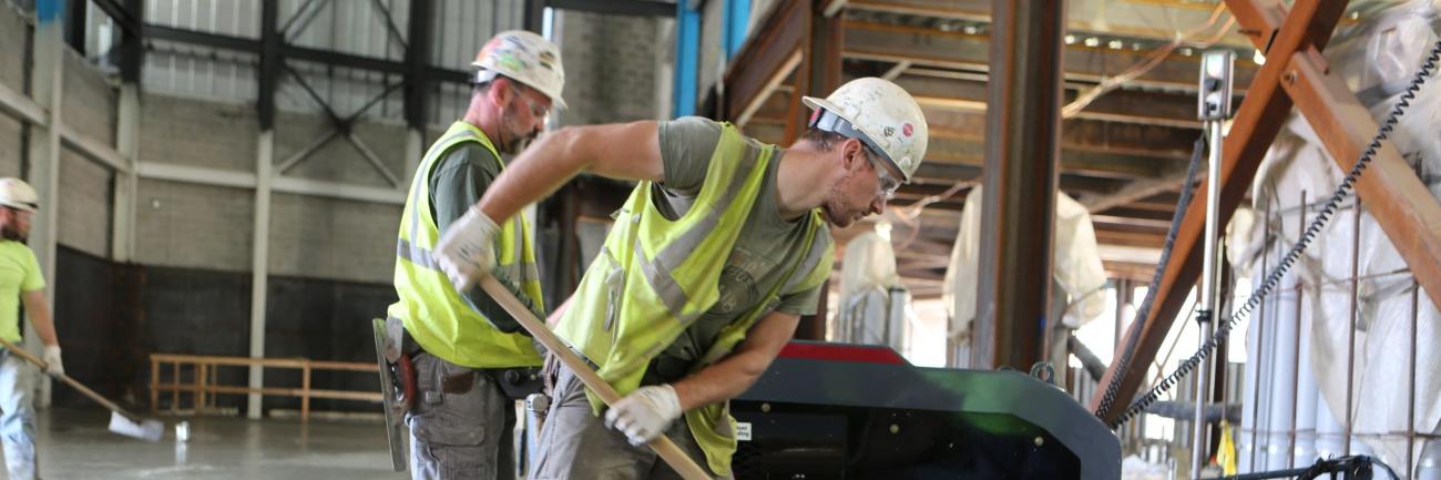 Two construction employees setting cement.