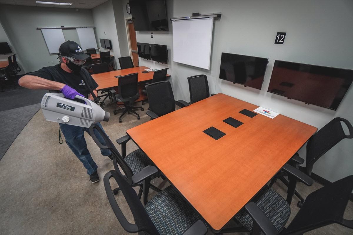 IPF Custodial Services' James Miller employs one of the new portable disinfectant misting units as part of his cleaning routine in one of Bott Nursing Building's classrooms. 