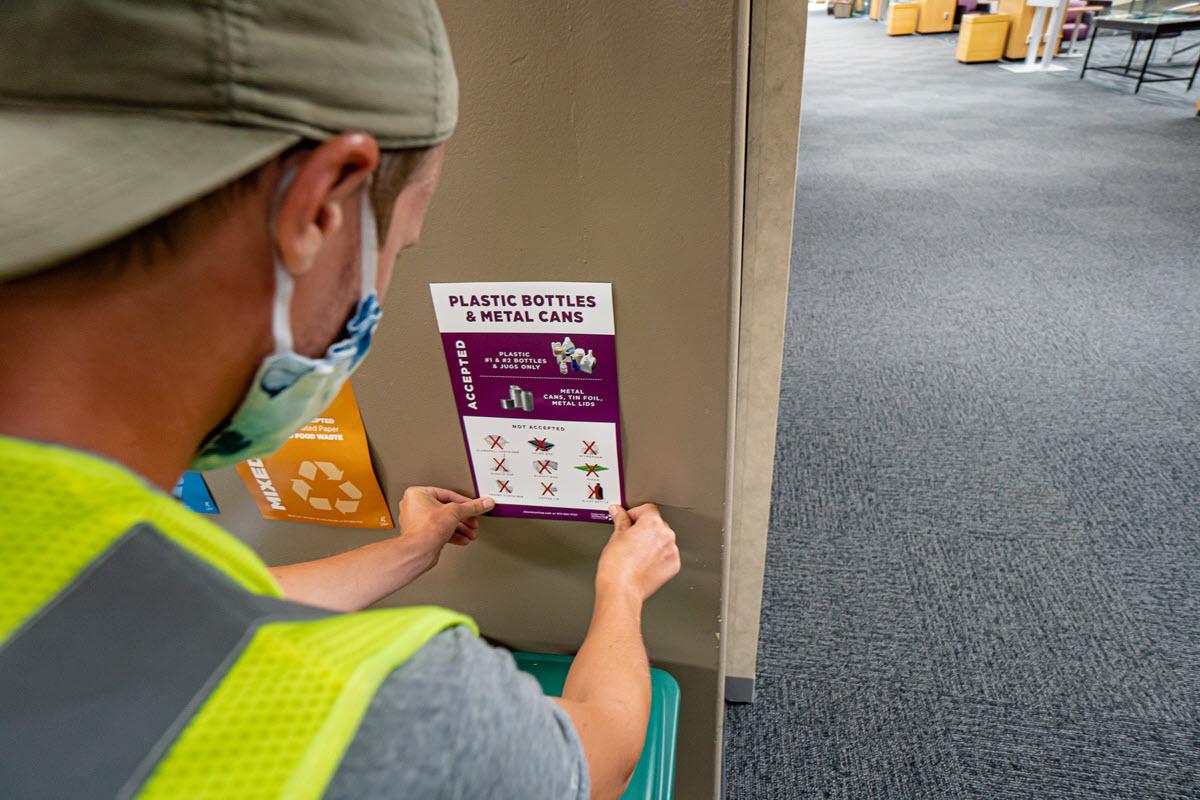 Konar Nokken, MSU Recycling driver collection/hauler, updates recycling stickers in the Library to comply with new recycling standards in response to COVID restrictions. 