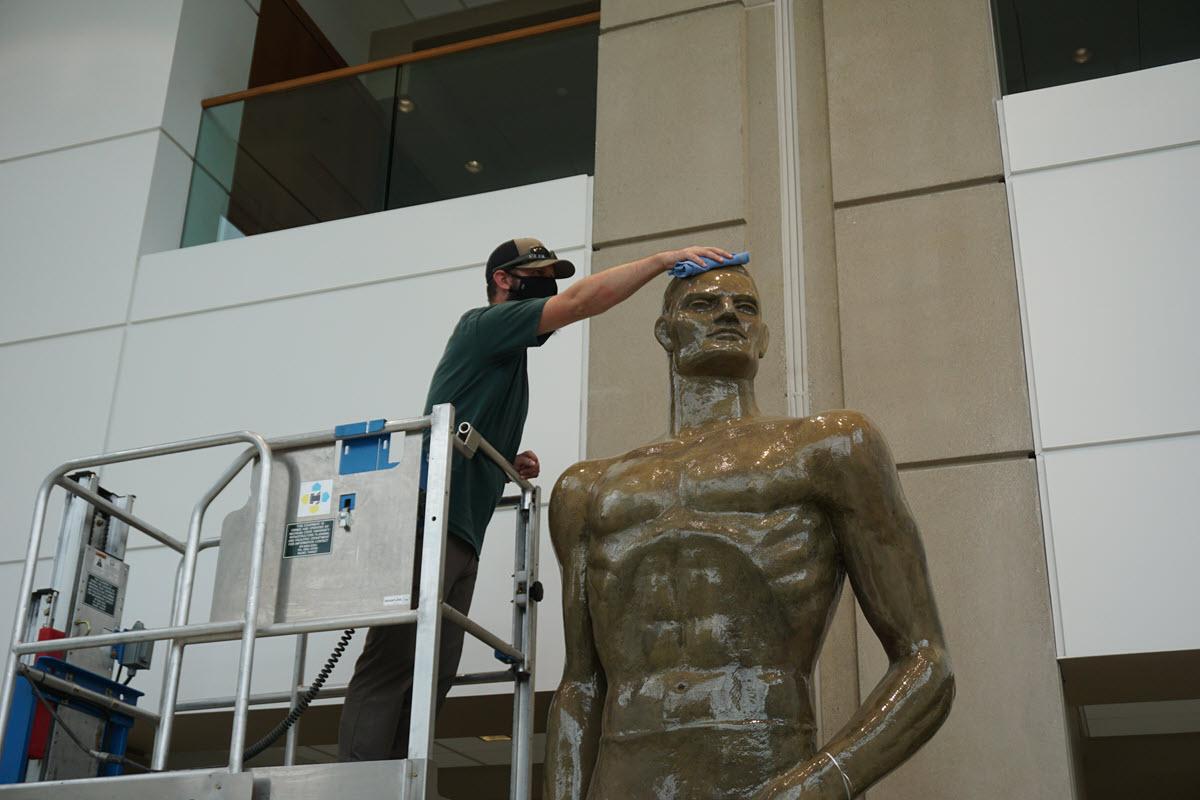 IPF custodial laborer, Justin Sutton gets the original terra cotta Sparty statue, located in Spartan Stadium, ready for football season.