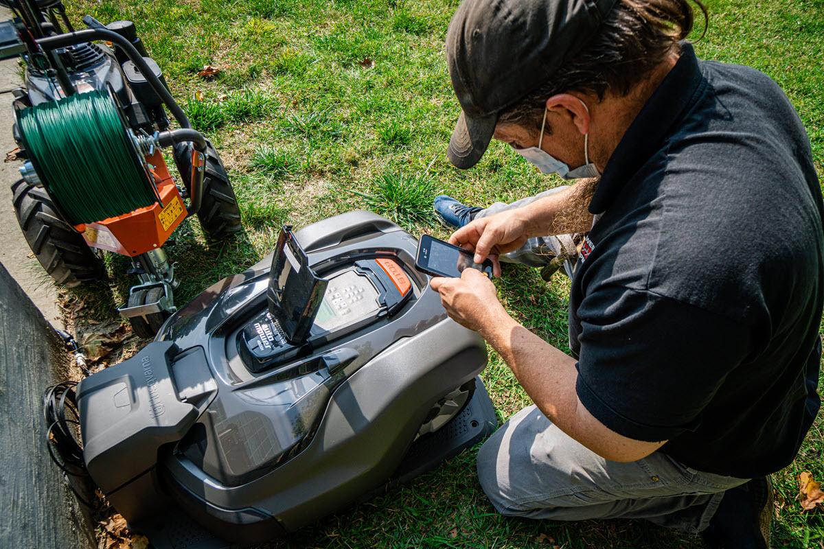 Service technician installing and programming new autonomous mowers to be used at Bryan/Brody Halls and Demonstration Hall.