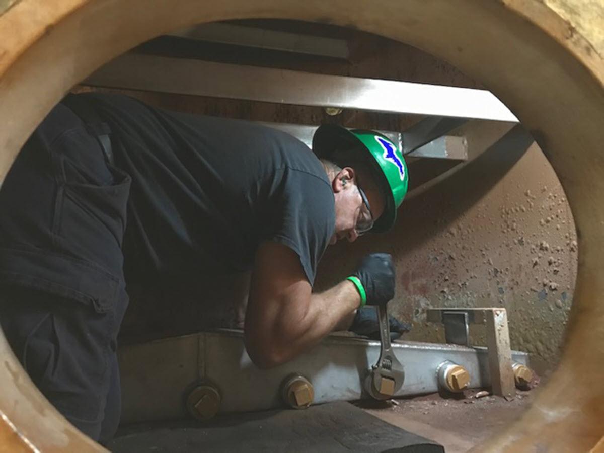 T.B. Simon Power Plant's Mike Thiry removes the internals of #3 condensate returns polisher so tank can be sent out for re-coating. Mike is working alone within in a permit-required confined space with a confined space attendant (not pictured) stationed outside and beyond the 6-foot social distancing guideline. A face mask makes it difficult for the employee working inside the confined space to communicate with the confined space attendant to coordinate and work safely. 