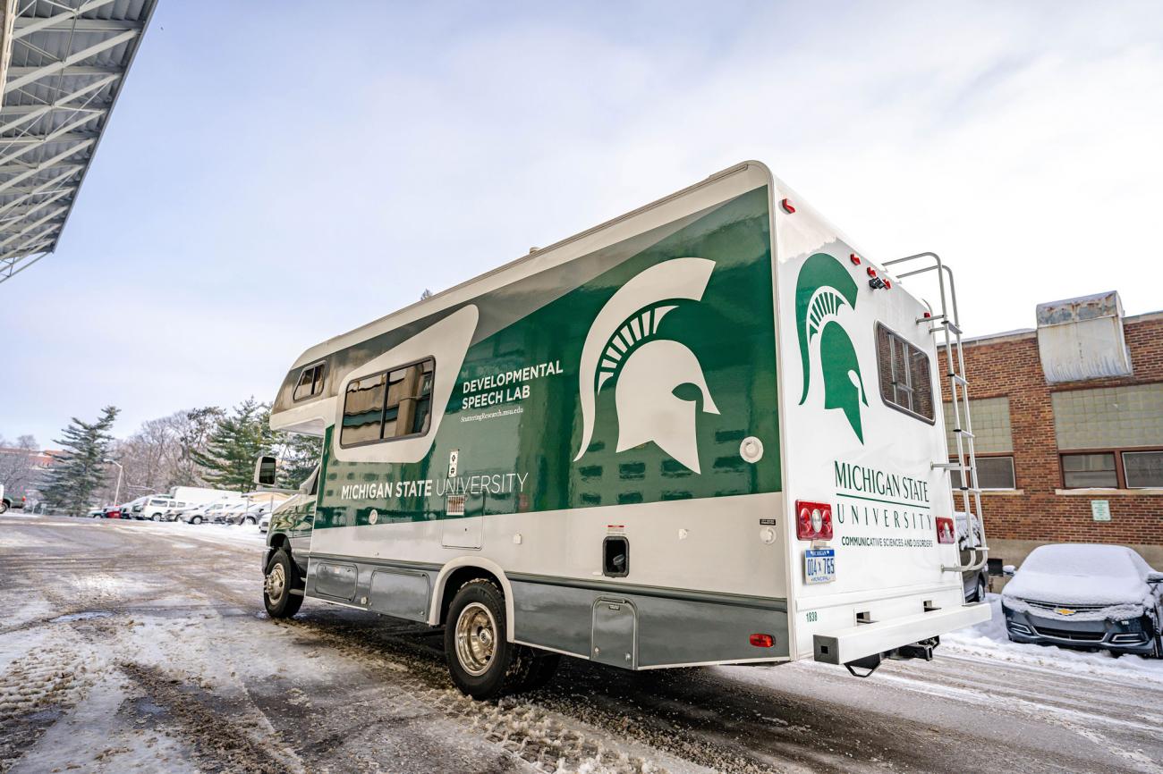 A standard size RV emblazoned with MSU green and Developmental Speech Lab wordmark