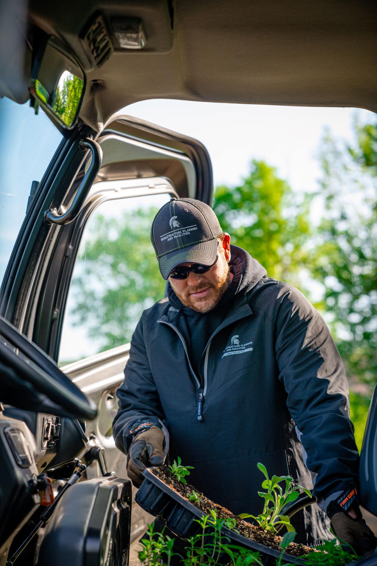 Josh Ridner wearing an IPF hat and jacket removes plant starters from a vehicle