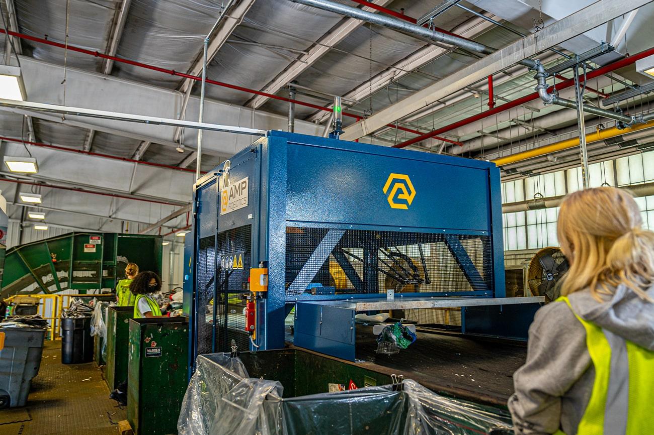 Workers at the MSU recycling center sort line with the robotic sorter.