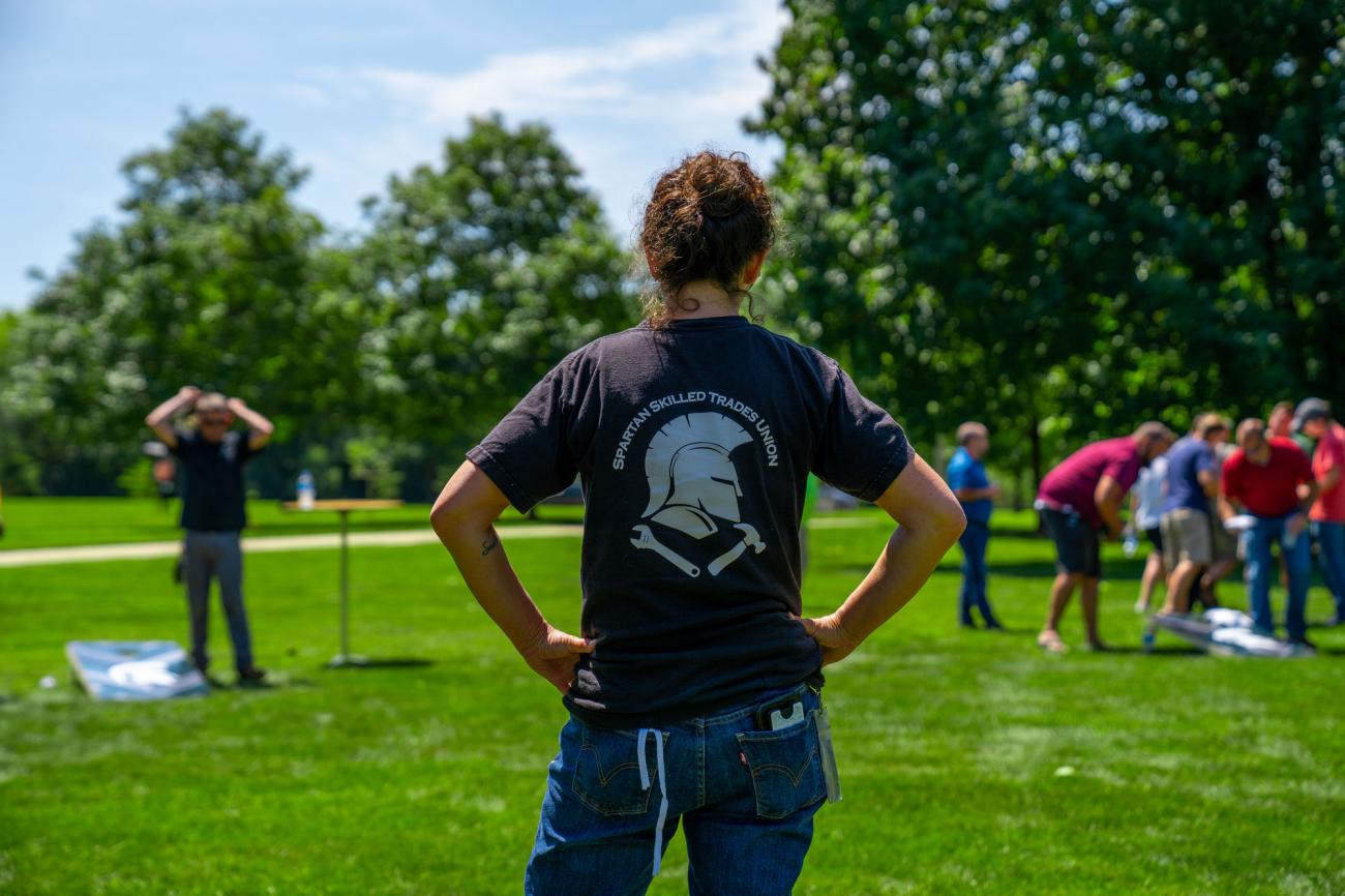 a woman stands in the sunshine wearing a tshirt for the Spartan Skilled Trades Union