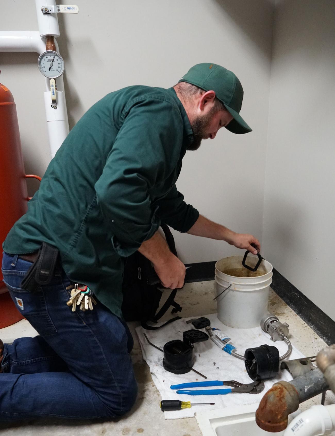 IPF plumber in green work shirt cleans a rubber gasket