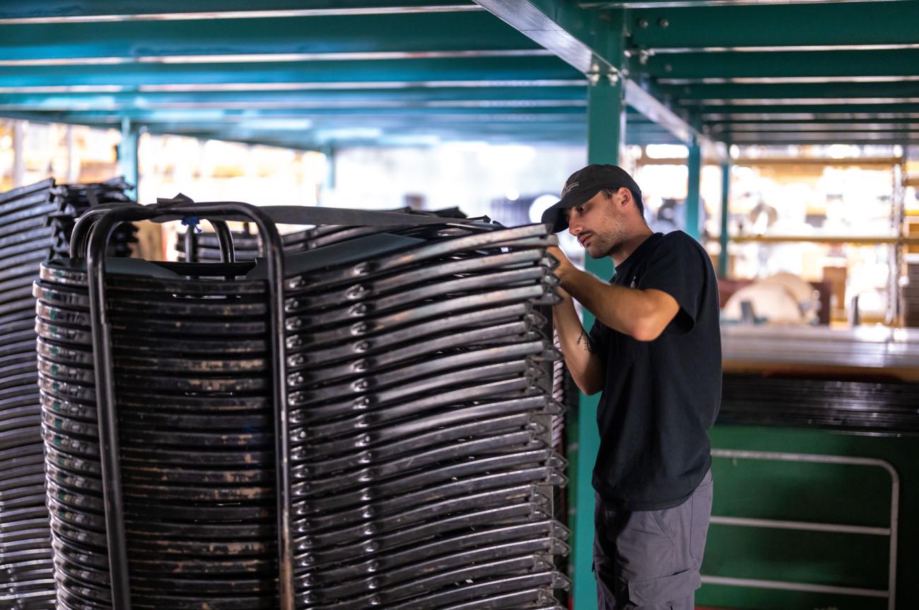 A man stands next to a tall stack of folding chairs