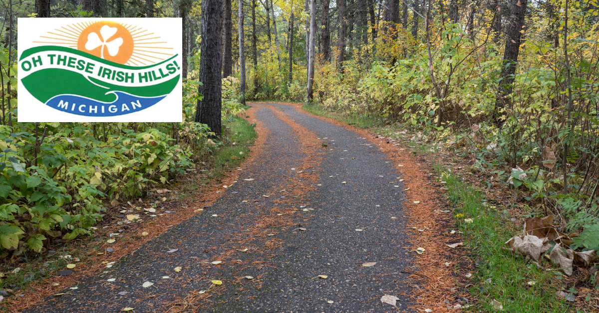 Path through woods with Oh These Irish Hills logo in upper left corner.